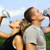 Man drinking water from a bottle outdoors after exercise