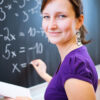 Young woman standing at a blackboard covered in maths equations
