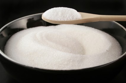 black bowl of plain white sugar with a wooden spoonful over it