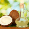 Halved coconut beside a bottle of coconut oil