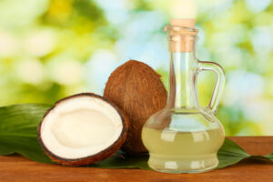 decanter with coconut oil and coconuts on green background